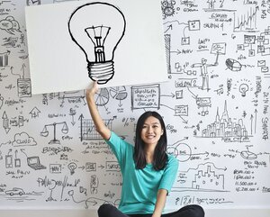 Frau mit White Board, auf dem eine Glühbirne zu sehen ist