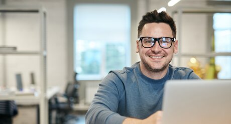 Ausbildung im zweiten Bildungsweg zum/zur Bürokaufmann/Bürokauffrau Angestellter sitzt im Büro vor seinem Laptop