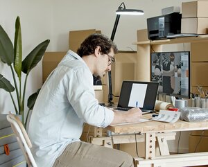 Mann sitzt an einem Schreibtisch und arbeitet an seinem Onlineshop