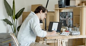 Mann sitzt an einem Schreibtisch und arbeitet an seinem Onlineshop