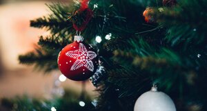 Rote Weihnachtskugel mit weißer Schneeflocke hängt an einem Tannenbaum