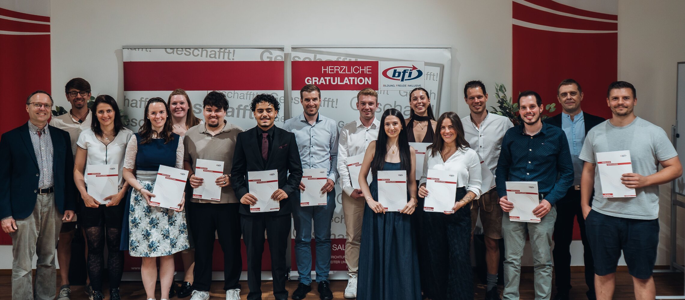 BFI-Absolventen mit Zeugnissen vor Banner in Salzburg