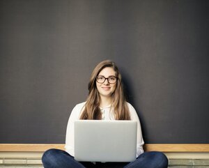 Studentin sitzt mit ihrem Laptop in einem Hörsaal
