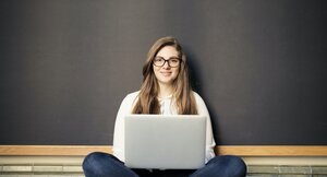 Studentin sitzt mit ihrem Laptop in einem Hörsaal