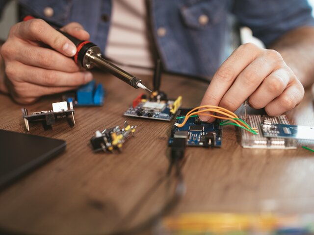 Elektrotechnik, KFZ- und Elektro-Mobilität Mann lernt eine Platine zu löten
