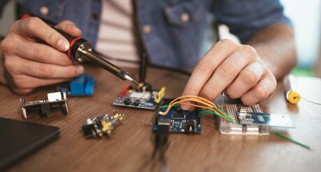 Elektrotechnik, KFZ- und Elektro-Mobilität Mann lernt eine Platine zu löten